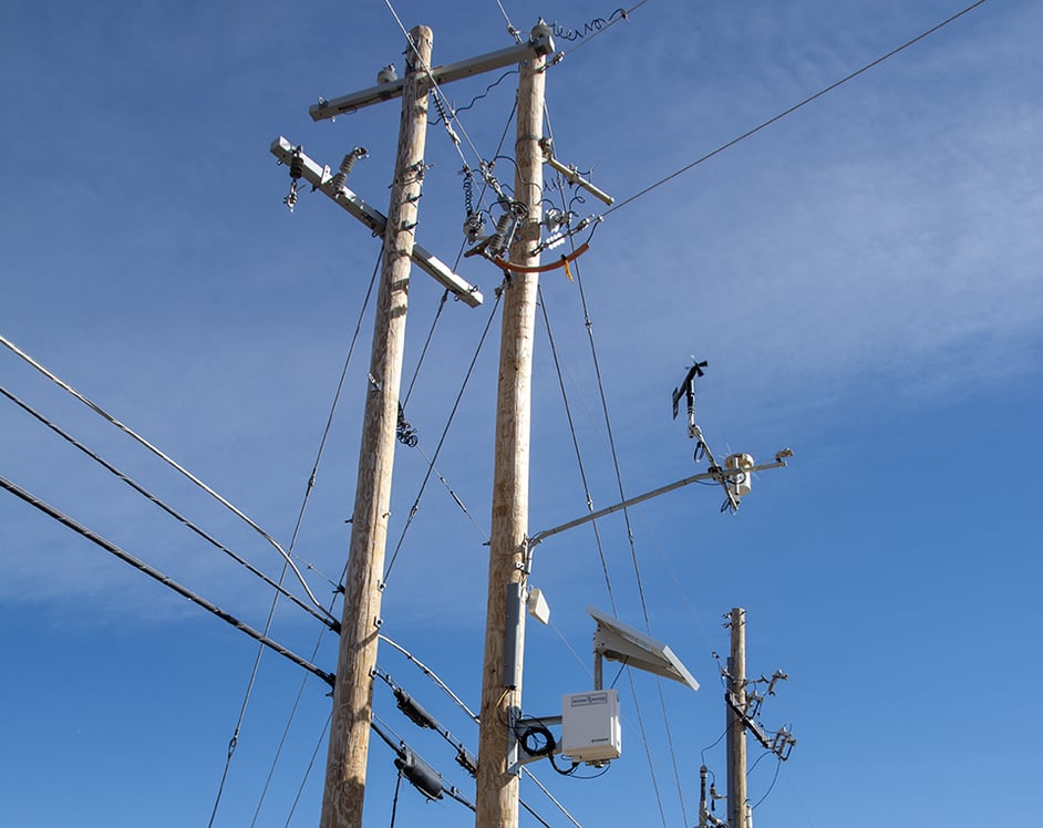 Another angle of a WWG weather station mounted on a utility pole against a blue, sunny sky.