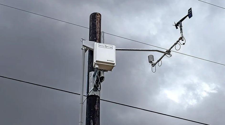 A Western Weather Group station mounted to a power pole against a stormy sky.